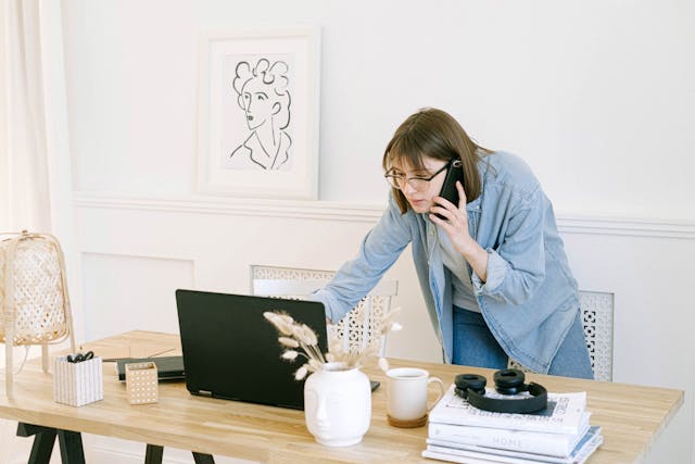 Person talking on phone and looking at a laptop